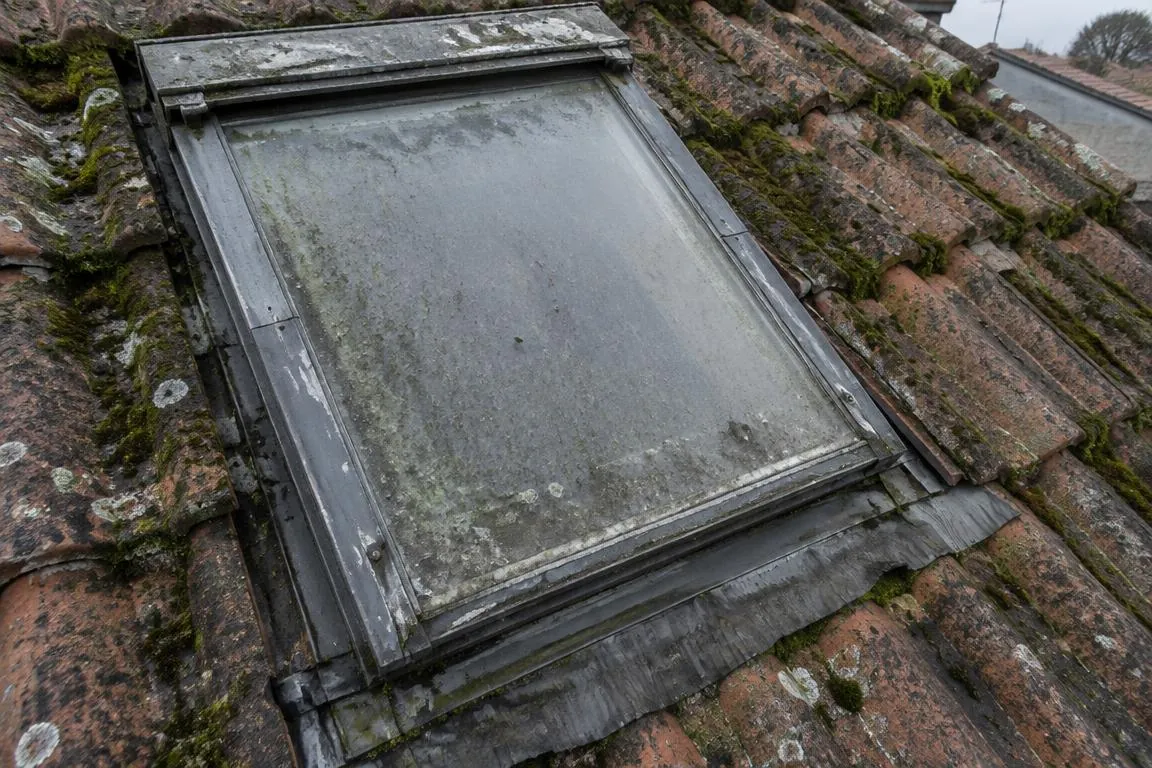 Fenêtre de toit avant et après remplacement : ancien châssis usé sur tuiles couvertes de mousse avant, châssis neuf avec solin neuf sur tuiles propres après — avant